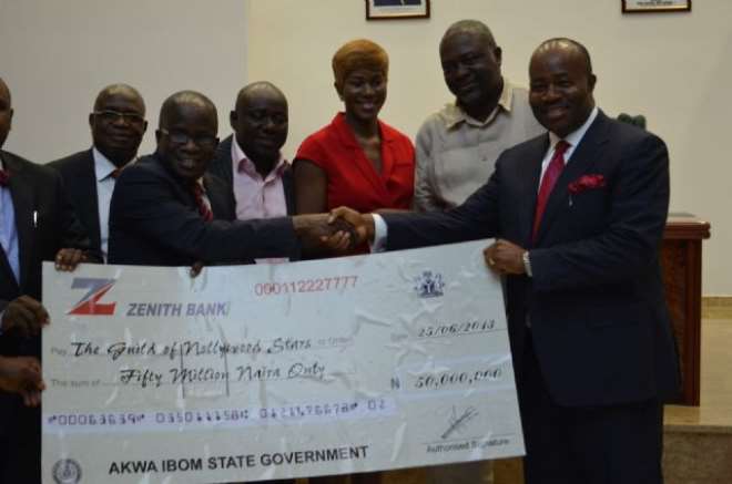 Gov_ Godswill Akpabio presentingh a cheque to Mr_ Zik Zulu Okafor, National President, Association of Movie Producers at Governor's Office, Uyo